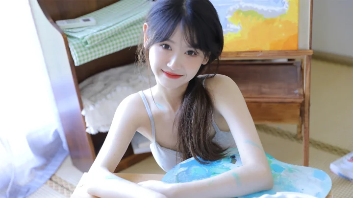 一名女性坐在室内床边，面向镜头微笑。