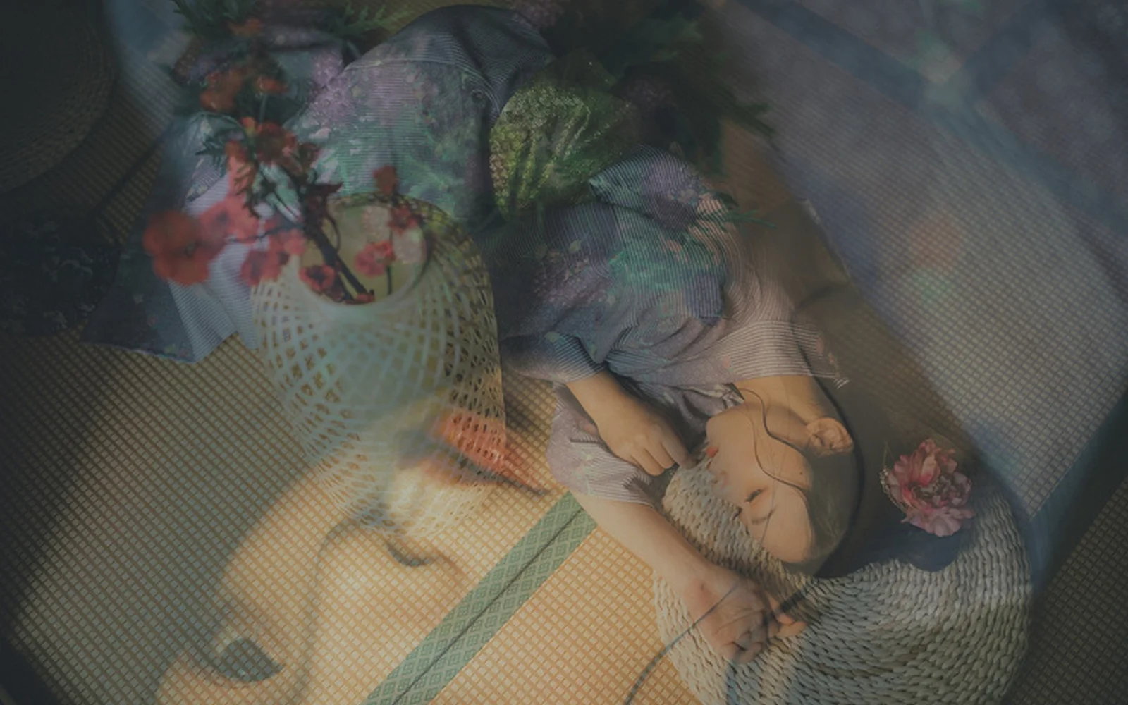 画面中一名女子闭眼侧卧在织物表面，花朵与半透明纹理叠加在她的身上和周围。