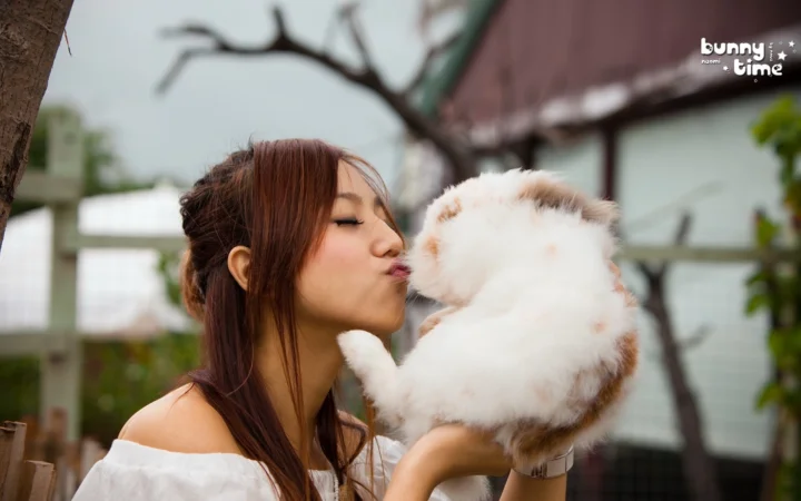 一名女子在户外亲吻怀中的白色毛绒猫咪。