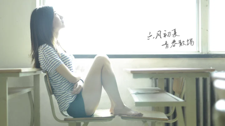 一名女性坐在明亮的教室窗边，阳光从窗外照入室内。