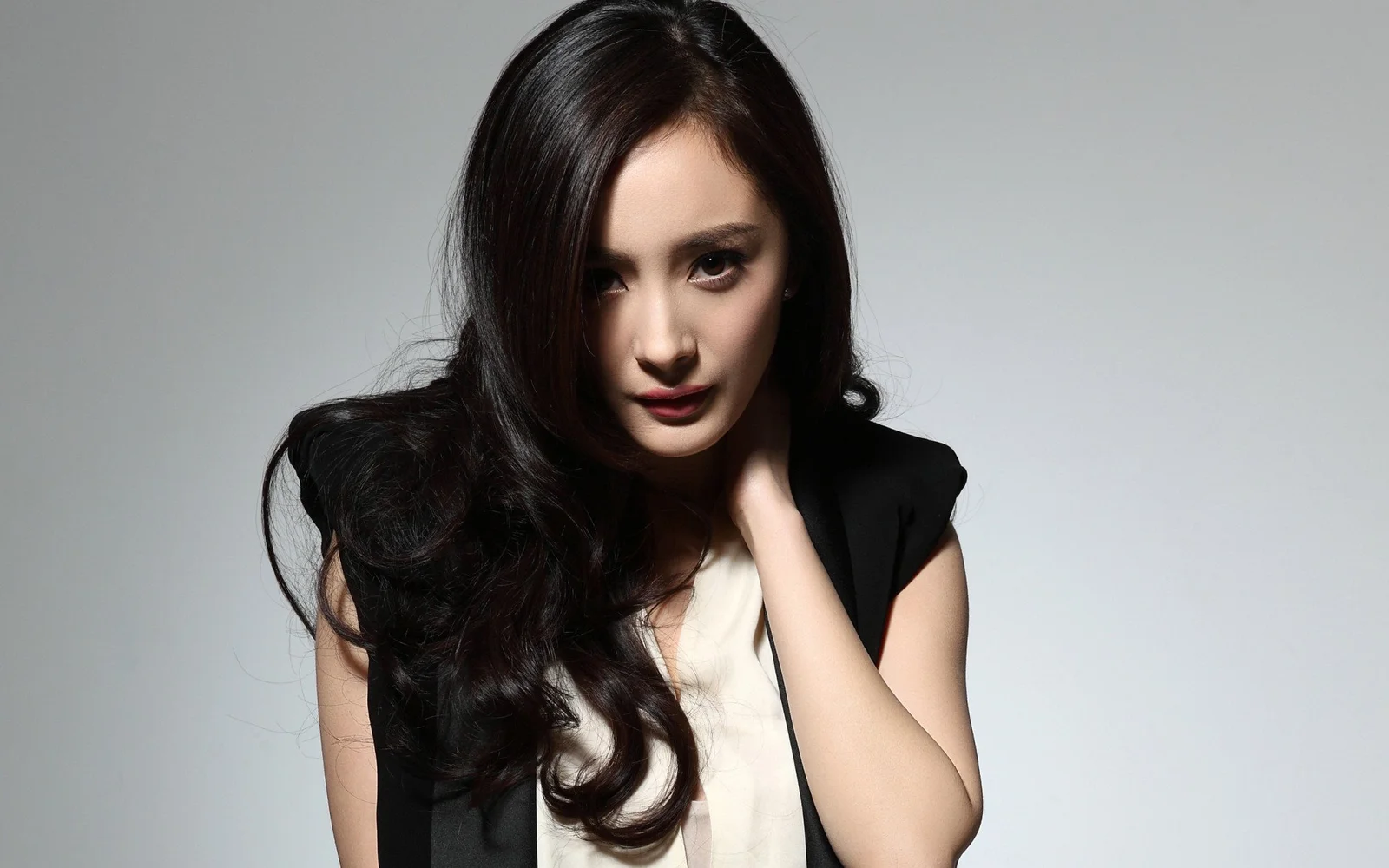 一名成年女性身穿黑色外套，在灰色背景前面向镜头摆姿势。