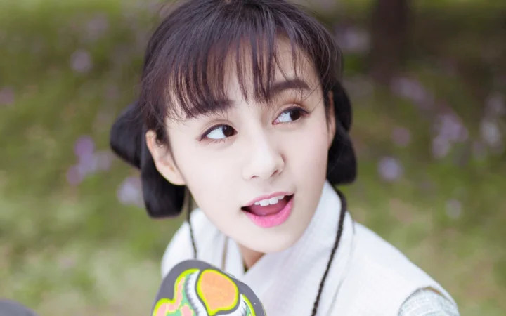 야외 배경 앞에서 여성이 옆을 바라보며 미소 짓는 클로즈업 초상이다.