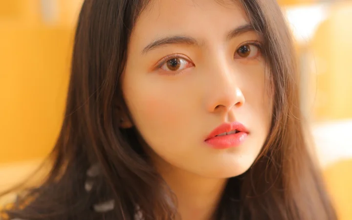 一位棕色长发女性的面部特写沐浴在温暖的金色光线中。