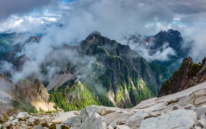 云雾笼罩的山脉延伸至远方，前景是裸露的岩石坡地。