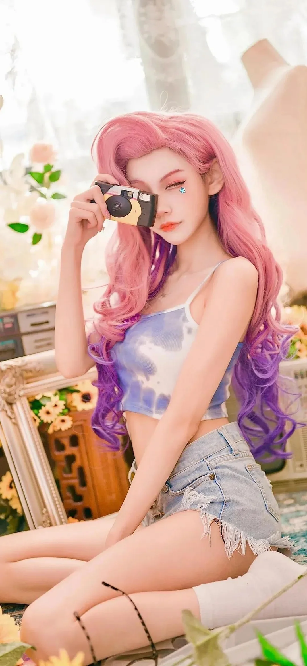 一位粉色长发的动漫风格女性手持相机坐在室内。
