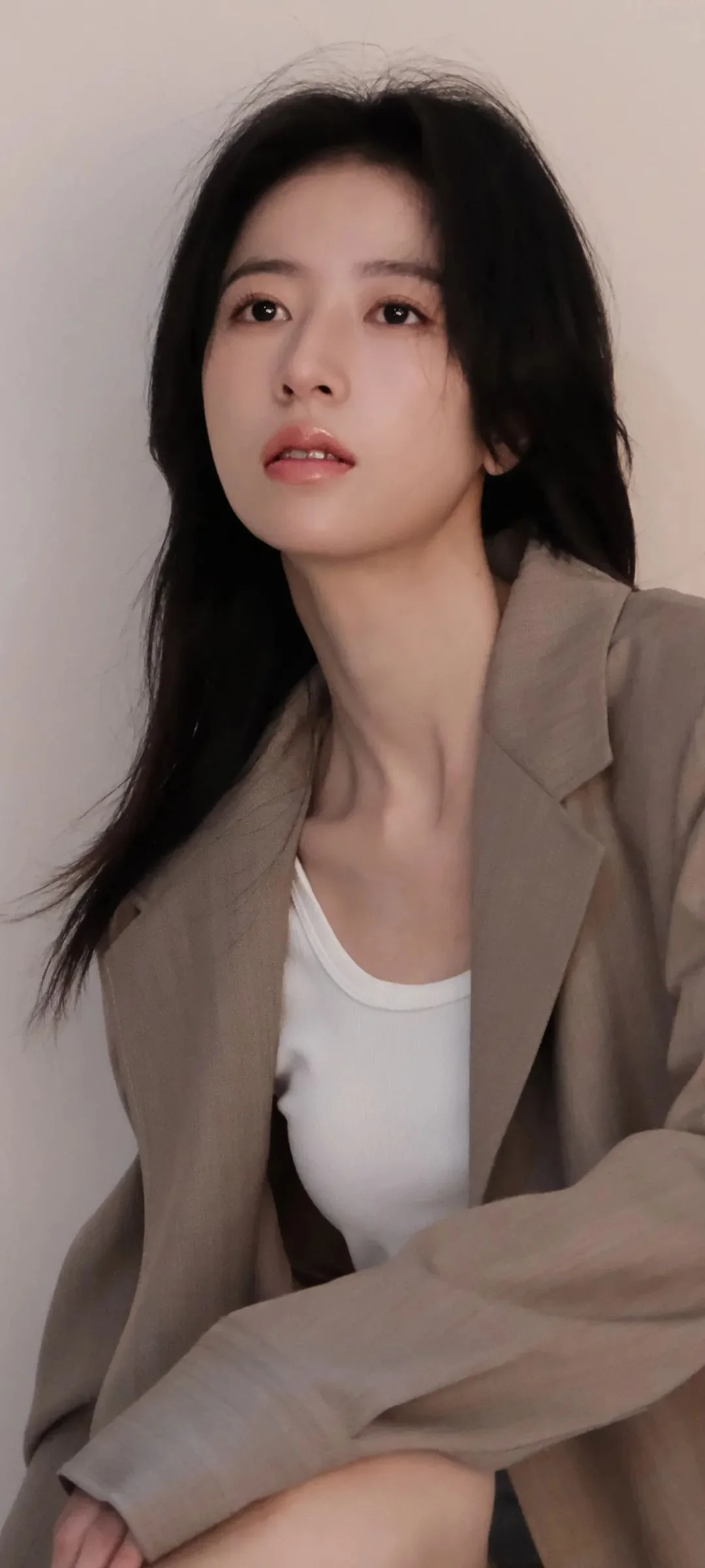 一位成年女性穿着米色西装外套和白色上衣，面对镜头拍摄肖像照。