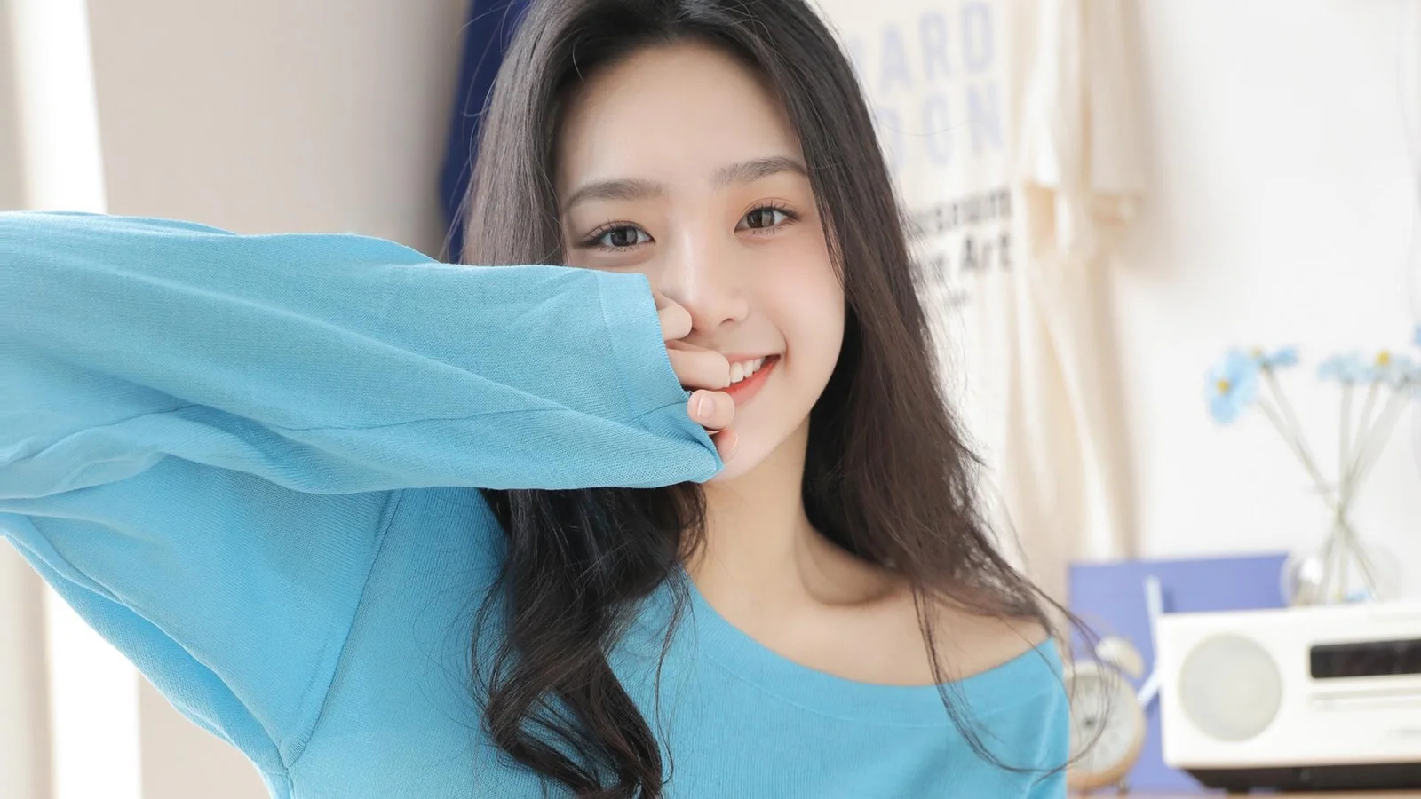 一名长发女子穿着蓝色上衣，微笑着看向镜头。