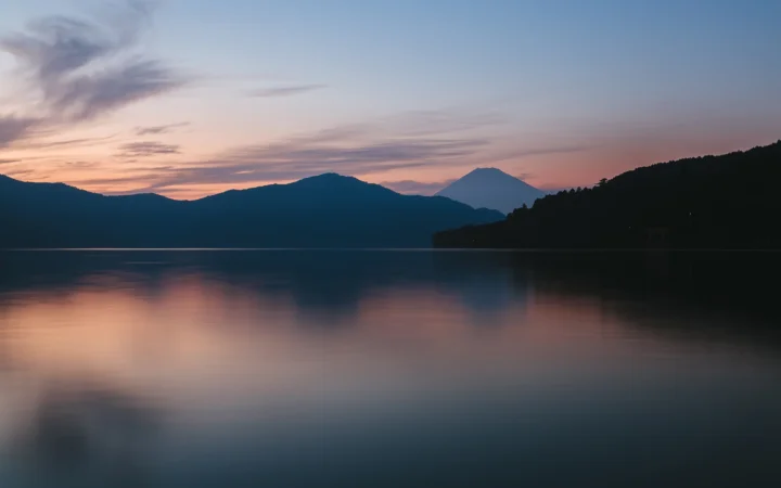 暮色天空映照在平静湖面上，远处山脉形成深色剪影。