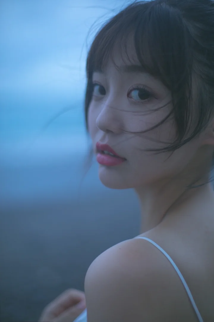 一位成年女性在蓝色柔光中回望镜头，发丝轻拂面颊。