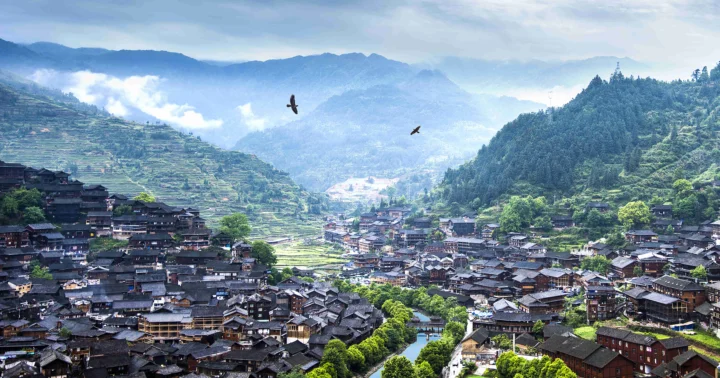 群山、梯田和密集的木屋村落铺展在云雾缭绕的山谷中。