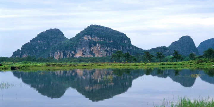 群山、湖泊与岸边植被倒映在平静的水面上。