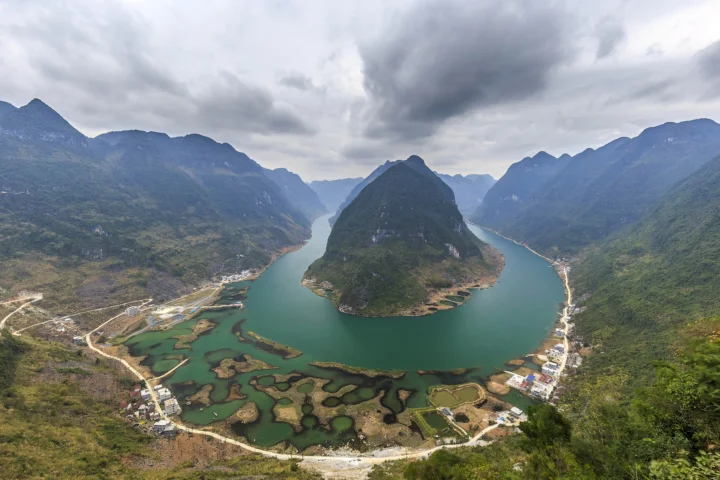航拍视角展现群山环抱的湖湾、蜿蜒水道与岸边村落。