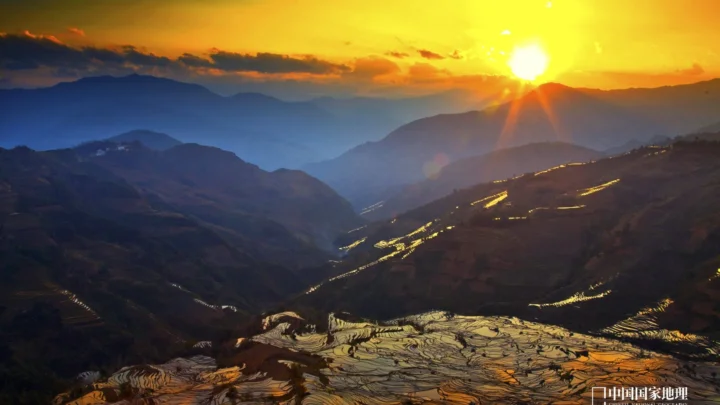 夕阳照耀下的群山与层叠梯田形成壮丽的山地景观。
