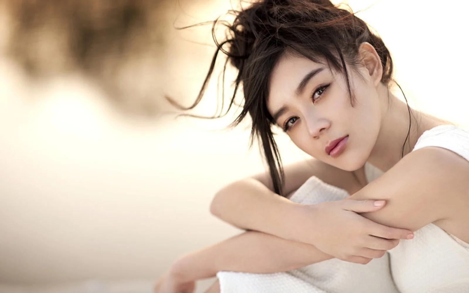 一名成年女性在柔和的暖色光线下抱臂注视镜头。