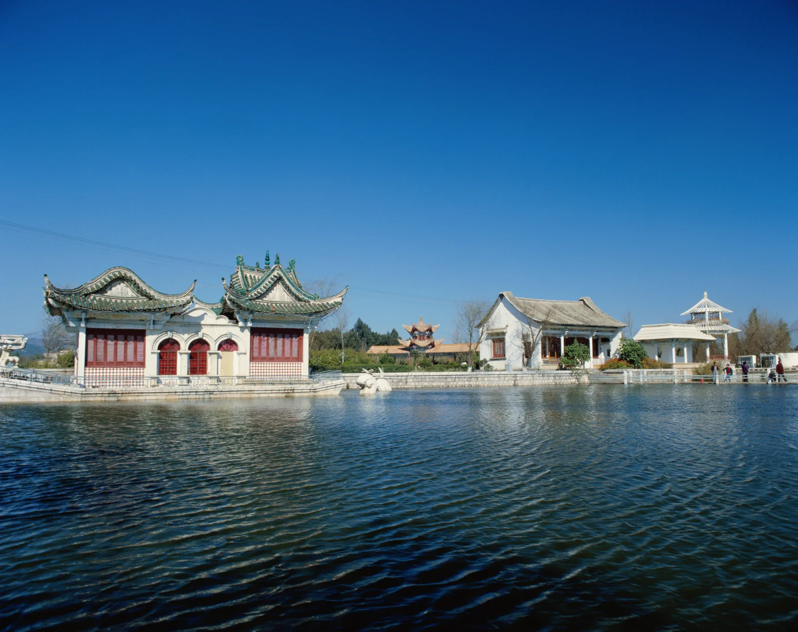蓝天下，湖水前坐落着一组传统中式古建筑与亭台楼阁。