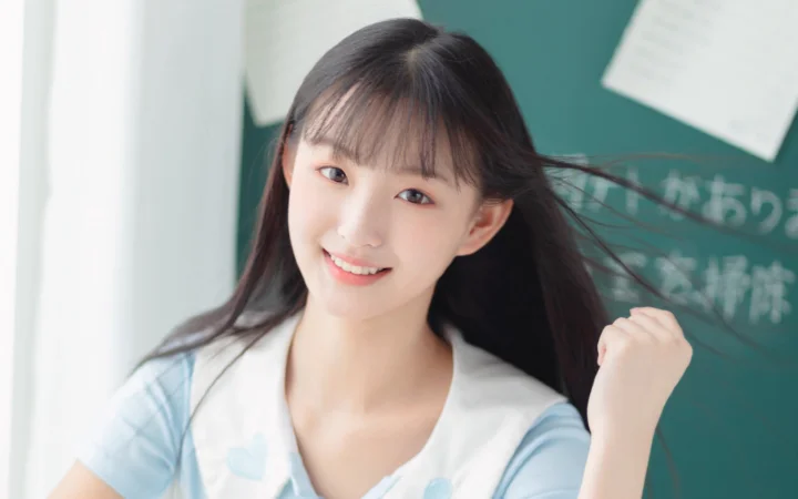一位长发微笑女性站在绿色黑板前。