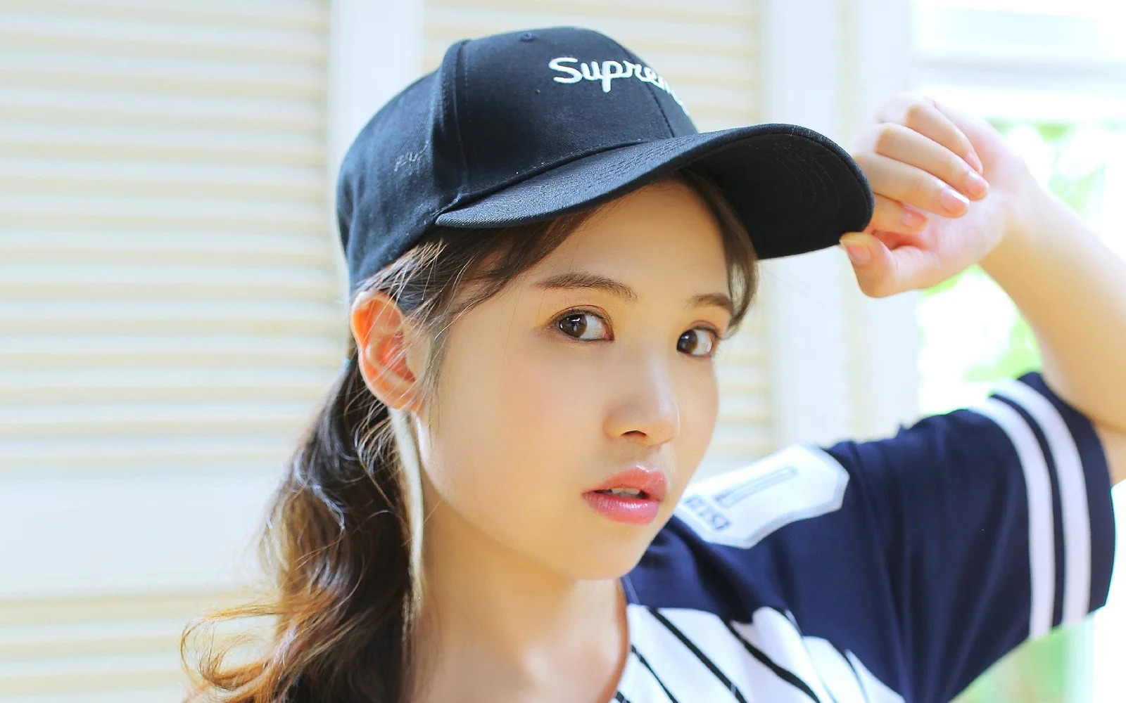 검은색 야구 모자와 운동복을 착용한 성인 여성이 실내에서 카메라를 바라보고 있습니다.