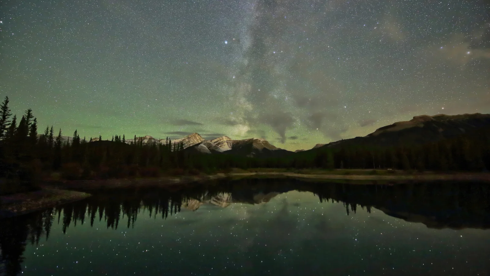 银河横跨夜空，远处山脉与湖面倒映出星光。