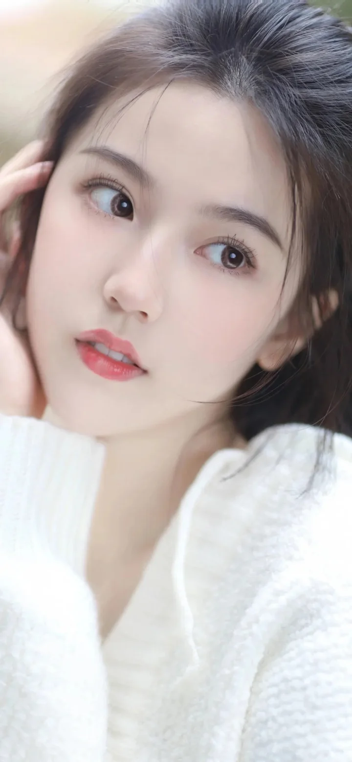 흰색 스웨터를 입은 여성이 카메라를 바라보는 부드럽고 자연스러운 클로즈업 인물 사진입니다.