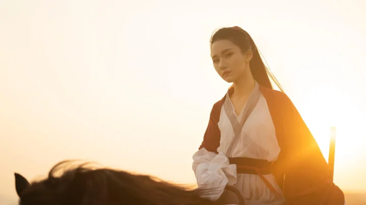 一名女子坐在马背上，沐浴在温暖的夕阳光线中。