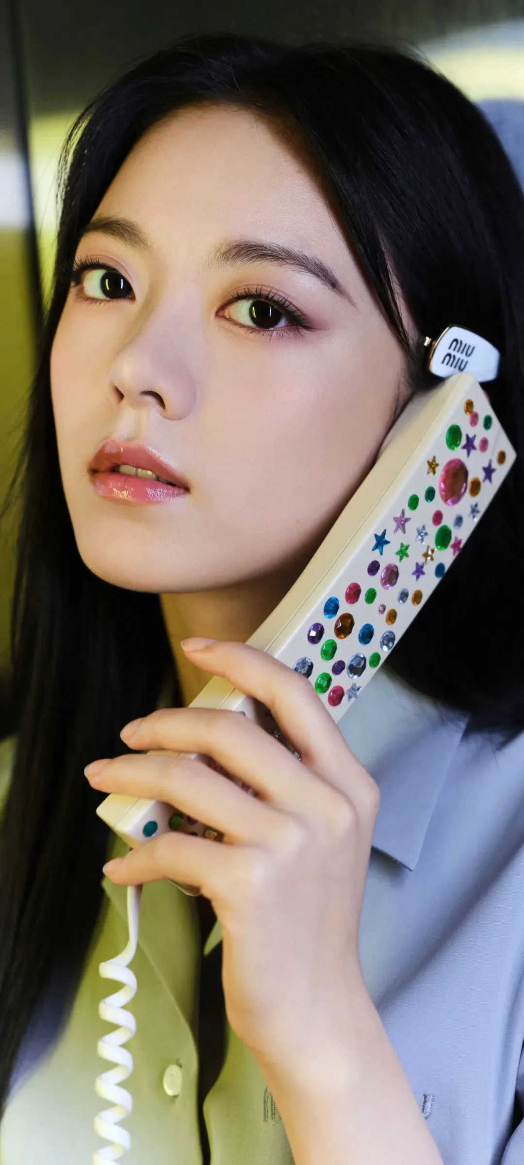 女性がカラフルな模様の電話の受話器を持ち、カメラに向かっている。