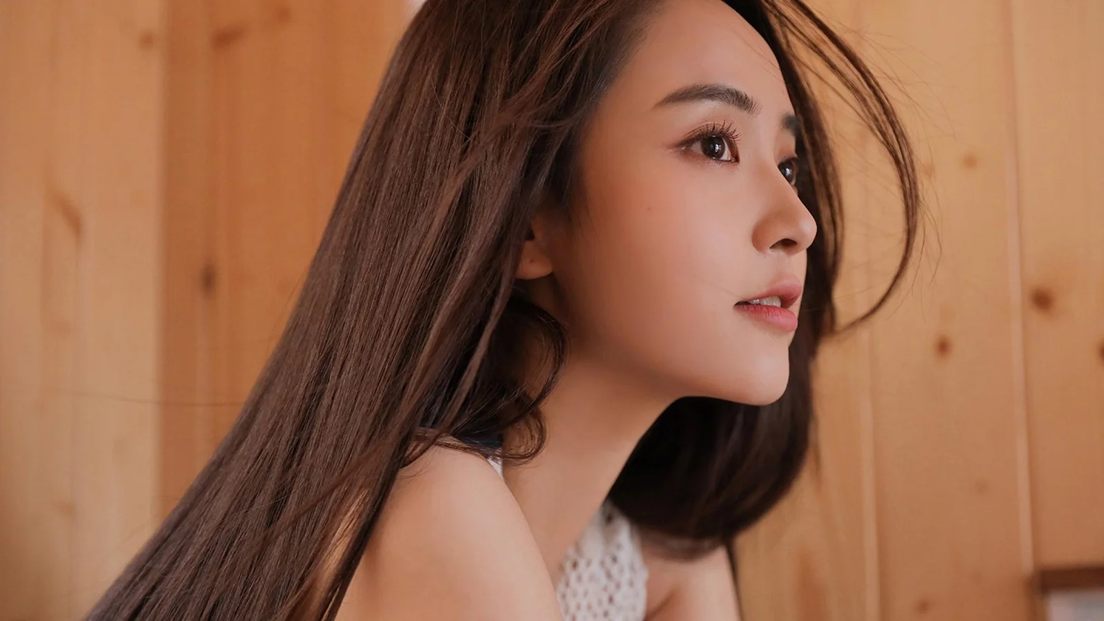 一名成年女性在木质室内背景前呈现自然的侧脸特写。