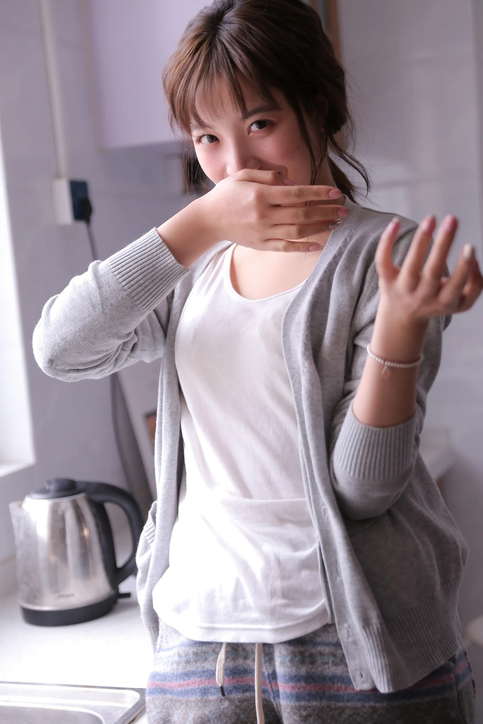 一名成年女性在室内穿着灰色开衫和白色上衣面对镜头。