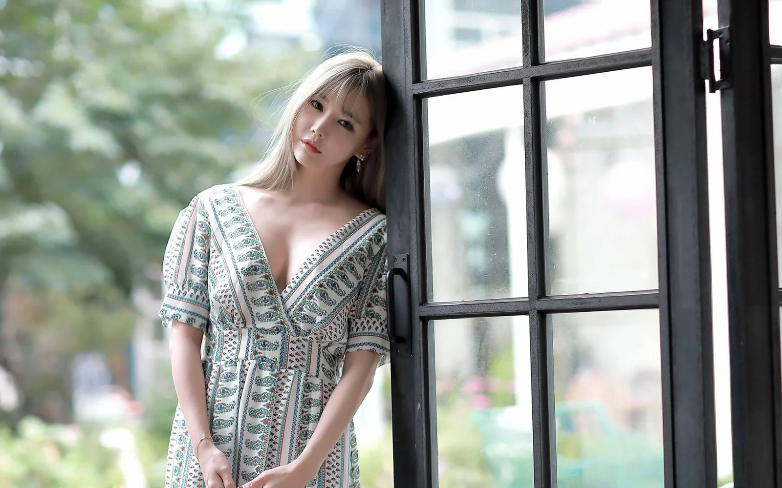 무늬 원피스를 입은 여성이 창가에 서 있다.