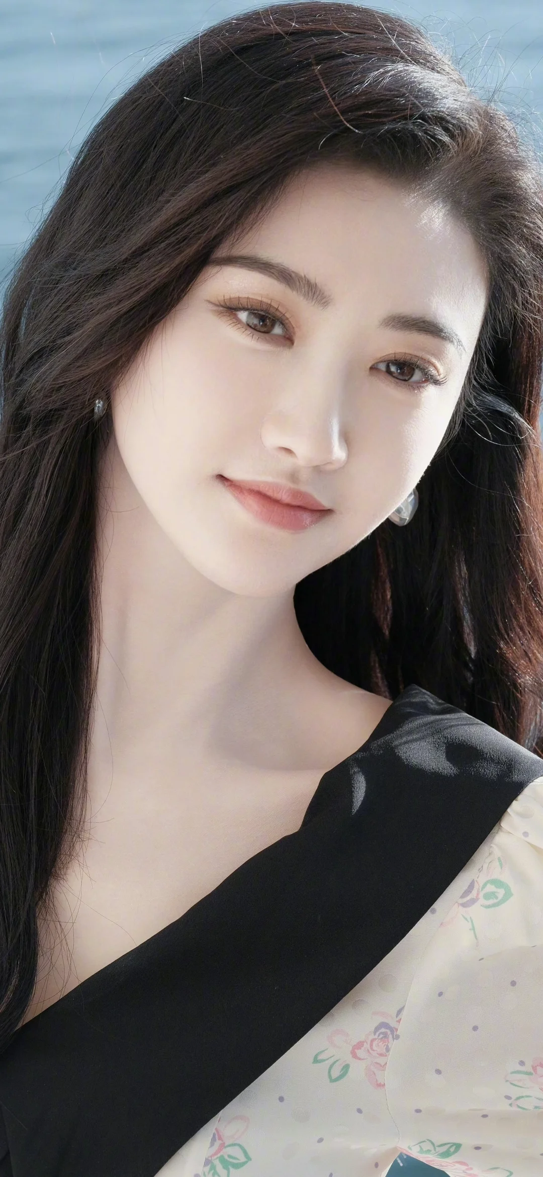 一位成年女性在自然光下身穿黑色服装面对镜头微笑。