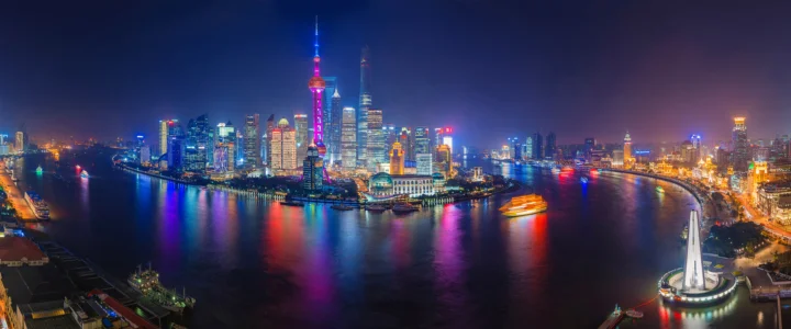 夜色中的上海城市天际线横跨江面，摩天大楼灯光倒映在水中。