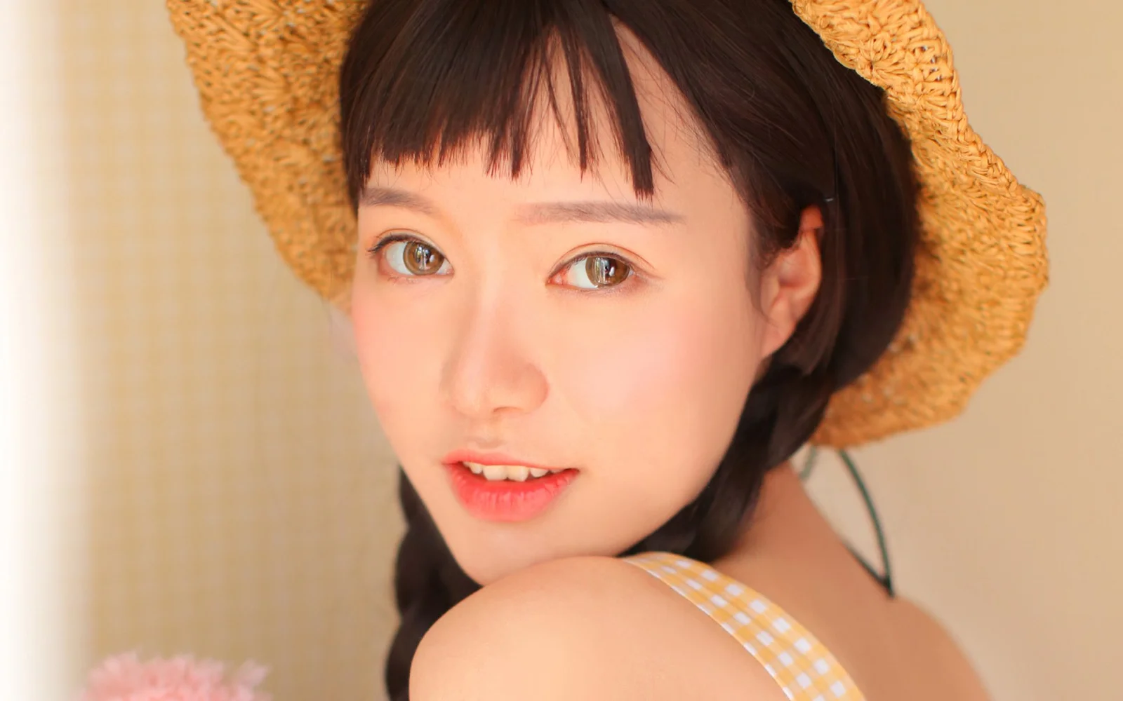 一位戴草帽的女性近距离面对镜头微笑。