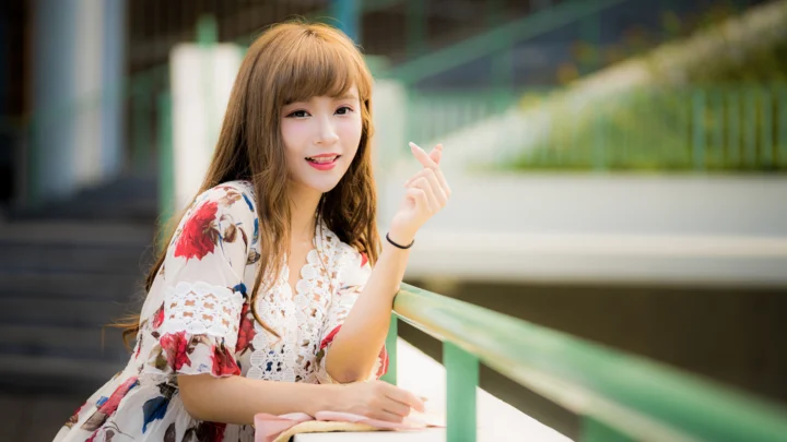 一名成年女性在户外栏杆旁微笑看向镜头。
