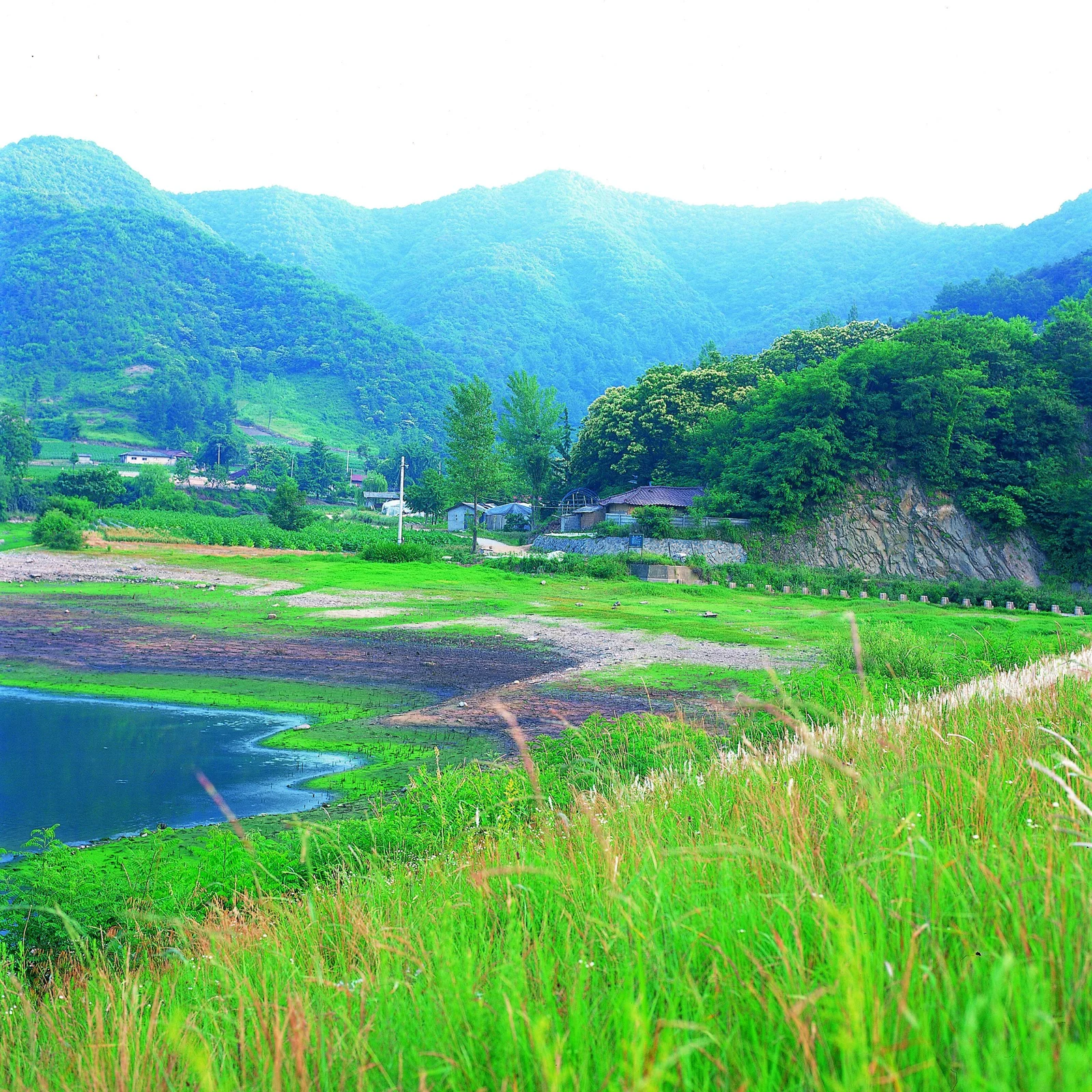 画面展现了青翠山脉、湖泊、田野和山村组成的宁静乡野风光。