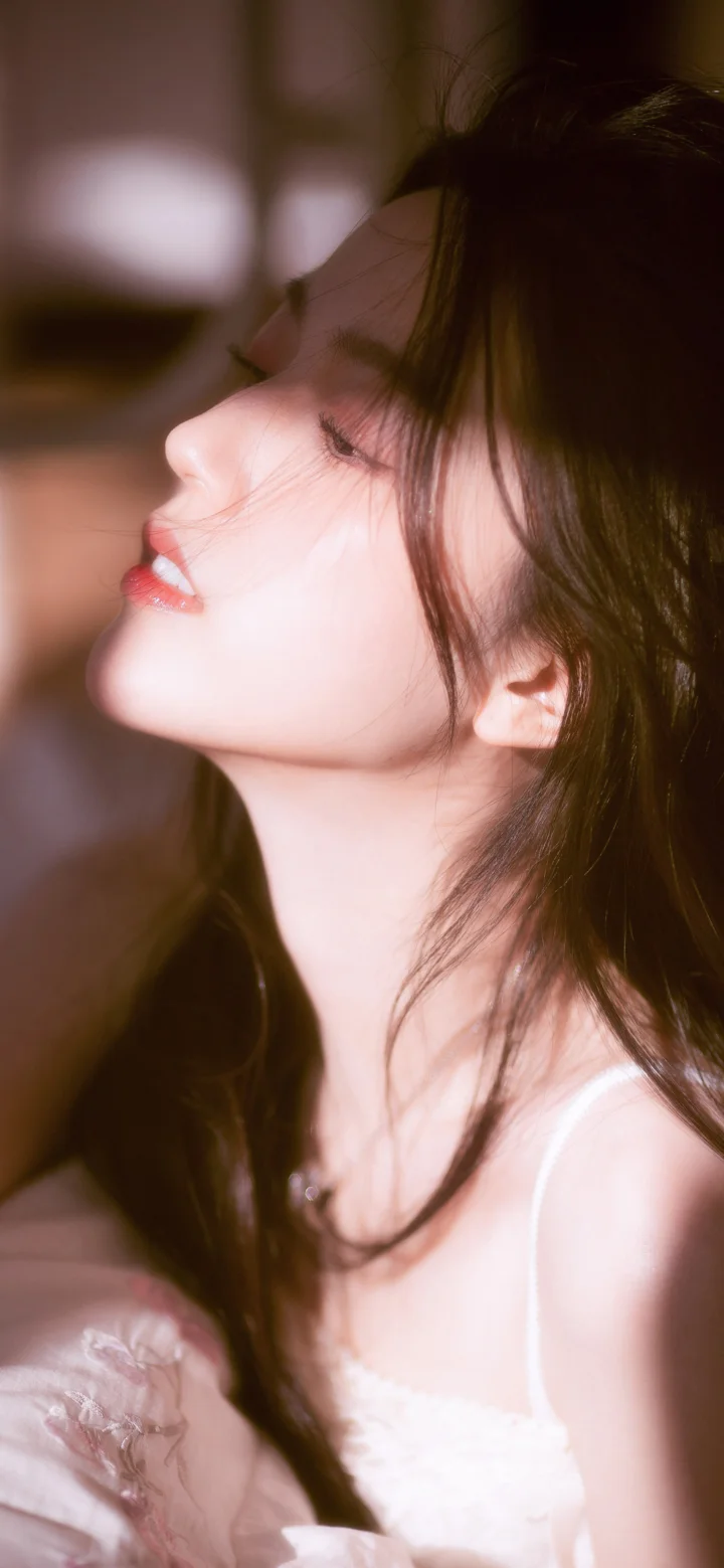 一名深色长发女性的侧脸近距离肖像，柔和光线勾勒出她的面部与肩颈轮廓。