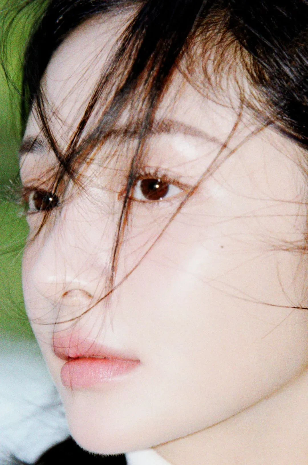 一名成年女性的近距离侧脸肖像，黑发散落在面部周围，画面突出她的眼睛和嘴唇。