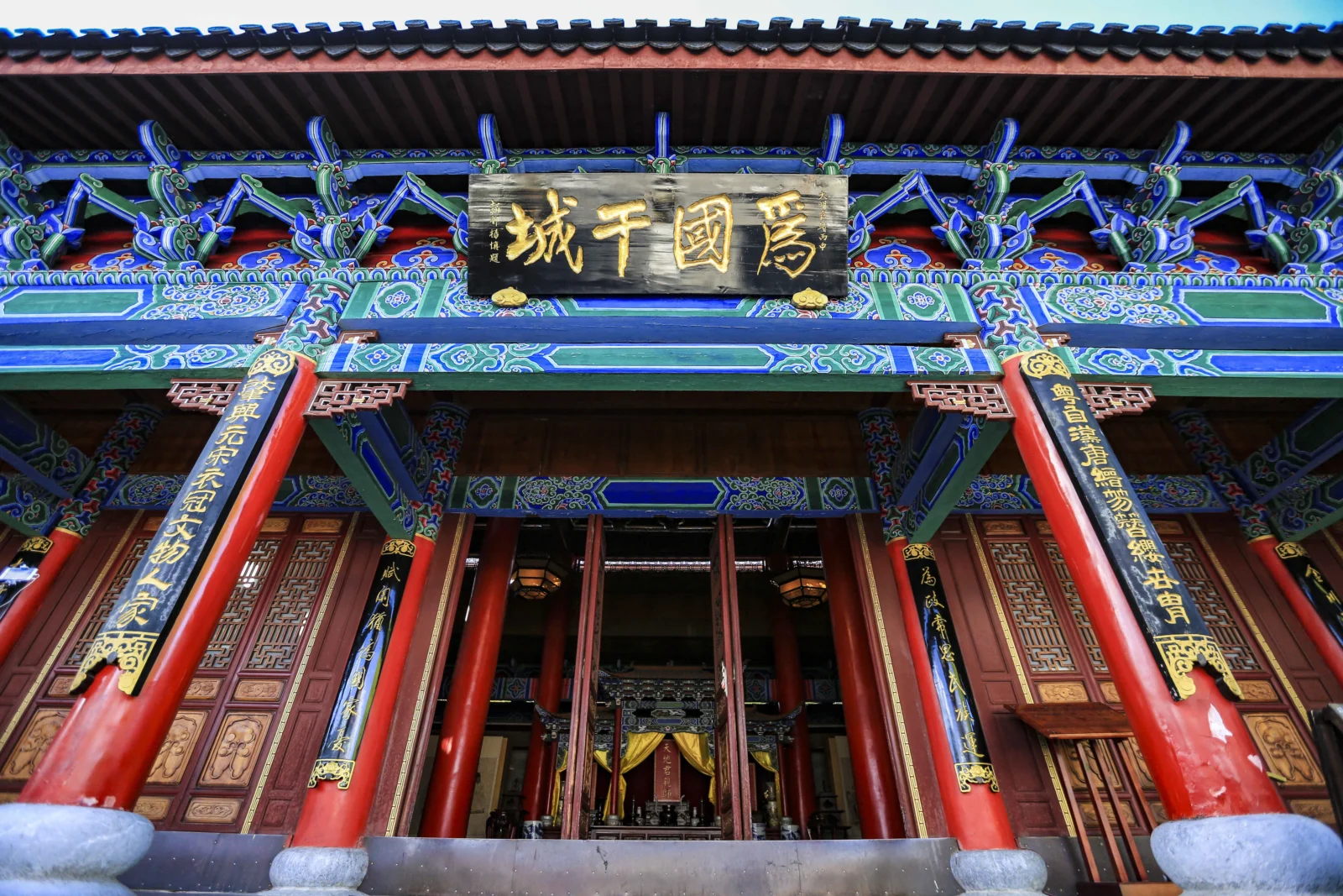 一座拥有红色立柱、蓝绿色彩绘装饰和金色牌匾的传统建筑门廊。