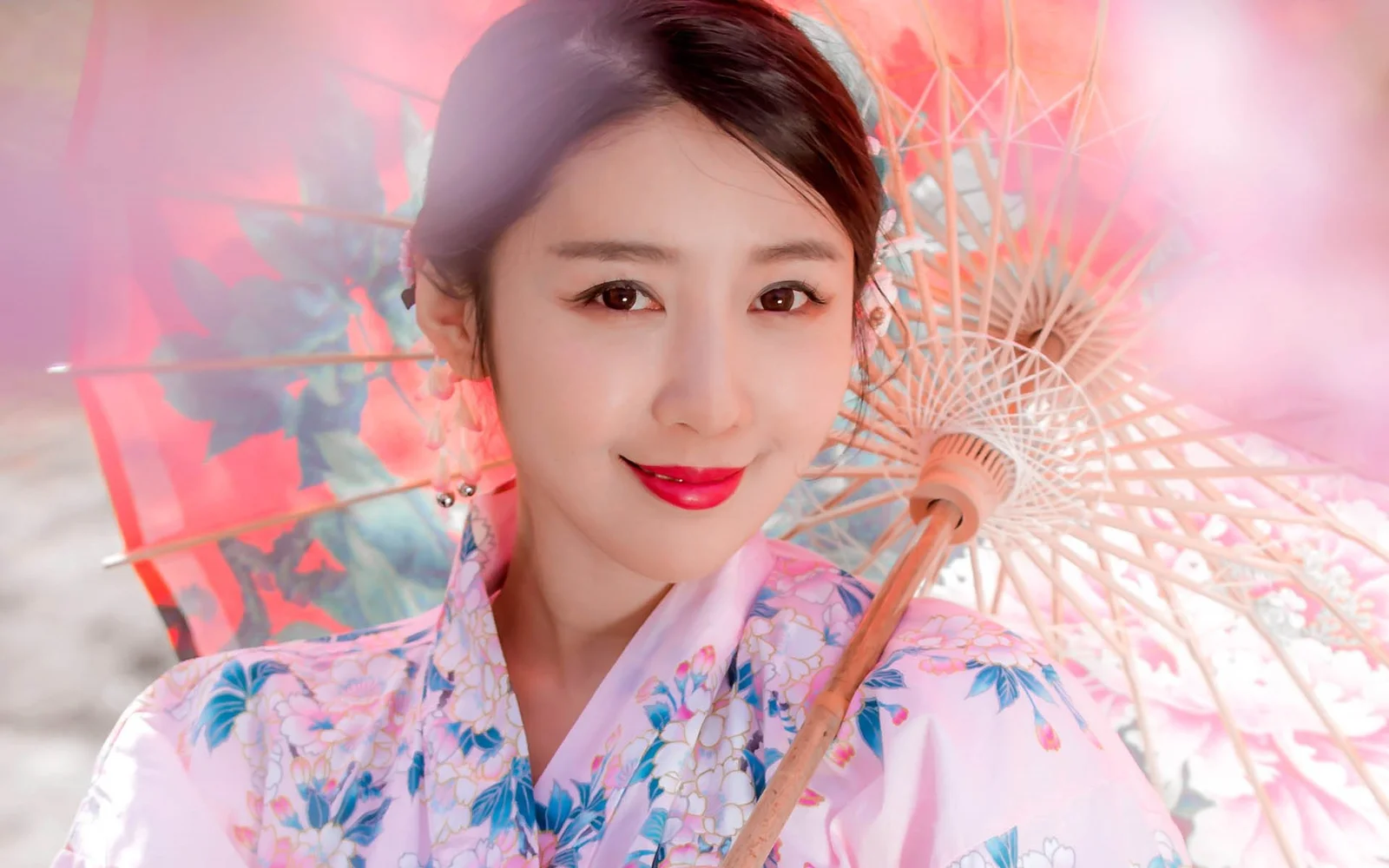 一位身穿花紋和服的女子手持和傘面對鏡頭微笑。