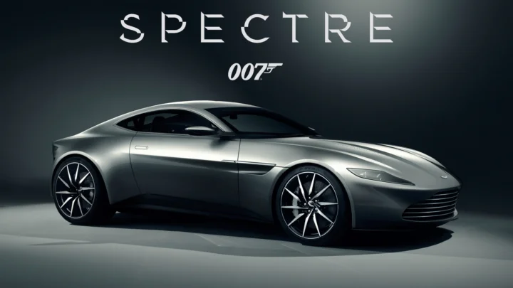 어두운 배경 앞에 은색 스포츠카가 보이며 위쪽에 “SPECTRE”와 “007” 문구가 표시되어 있습니다.