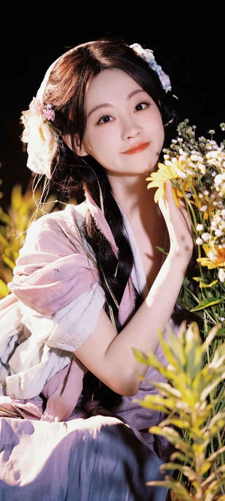 一位身穿浅色衣裙的成年女性在花丛中手捧花束。