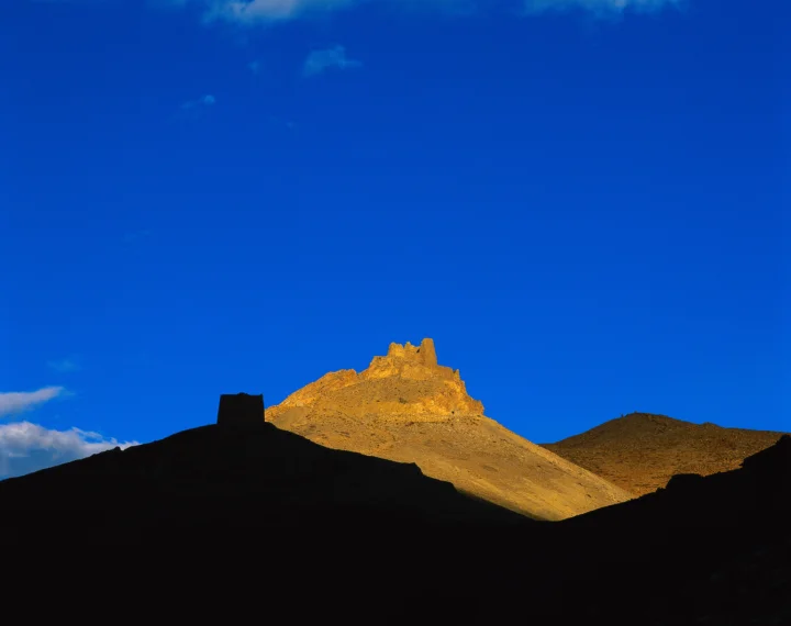 金色山峰在深蓝天空下被夕阳照亮，前景呈现深色山脊轮廓。