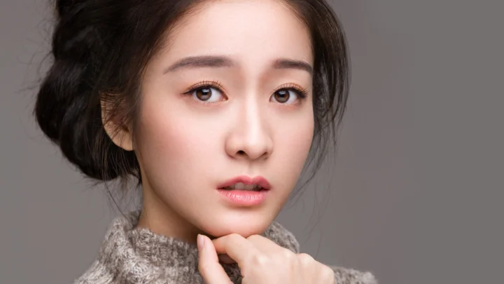 회색 배경 앞에 있는 성인 여성의 클로즈업 초상화입니다.