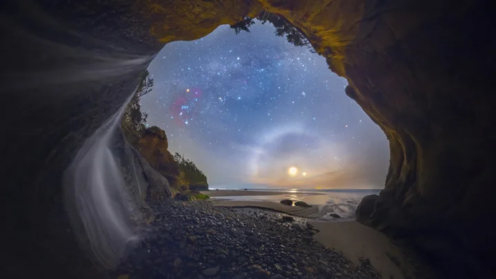 洞穴内可见瀑布、海滩、海面和被星空照亮的月夜天空。