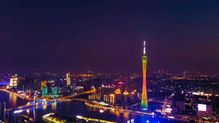 夜幕下的城市沿江灯火璀璨，中央高塔映照在珠江水面上。