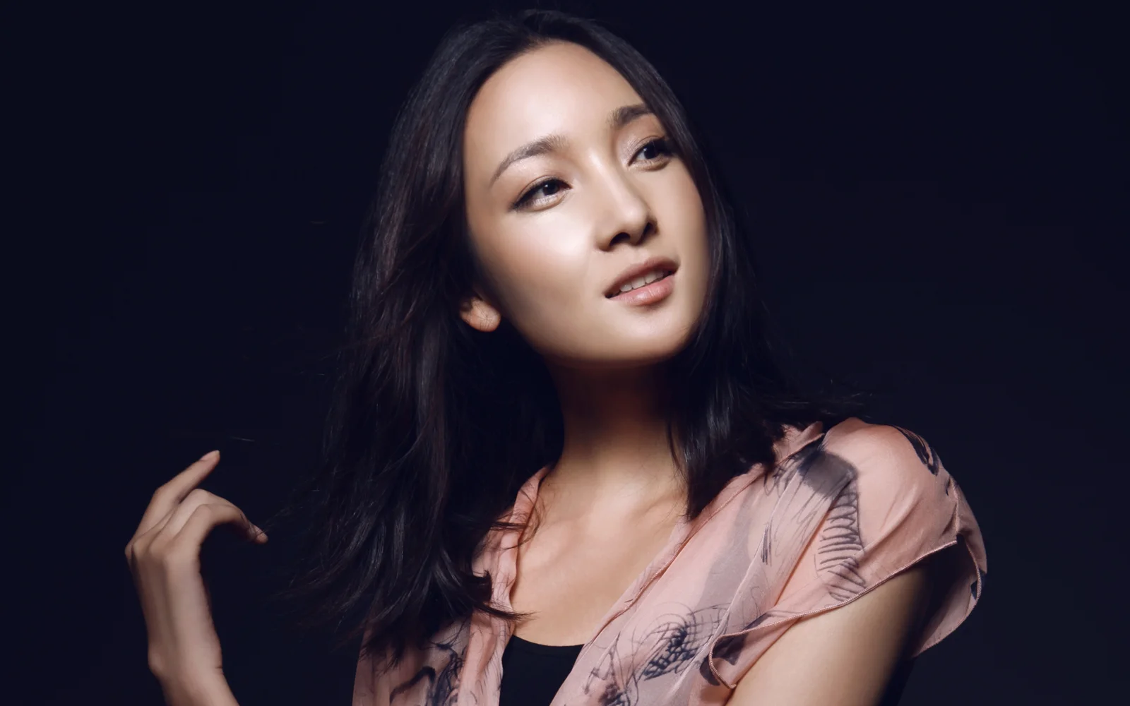一名成年女性在深色背景前进行室内肖像拍摄。