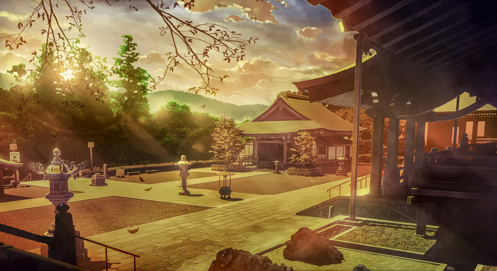 夕日に照らされた日本の神社の境内に、木々や石灯籠、伝統的な建物が見えます。