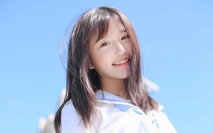一位长发女性在明亮的蓝色背景前微笑。