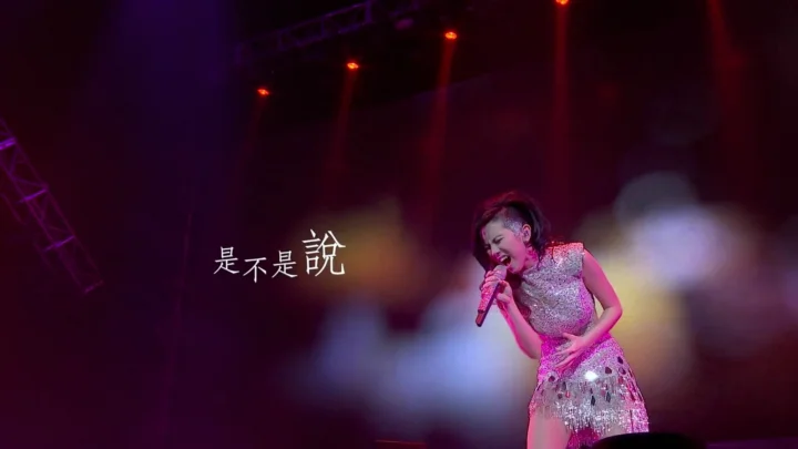 一位歌手手持麦克风在紫红色舞台灯光下演唱。