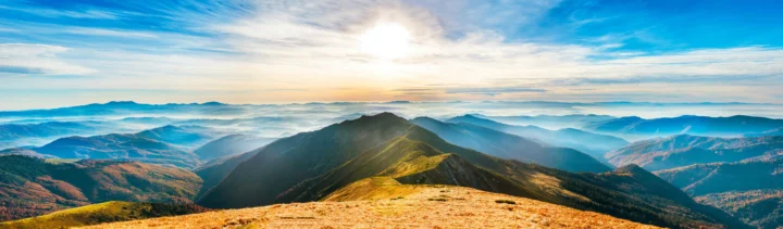阳光照耀着层叠山脉与金色山脊，呈现出壮阔的全景风光。