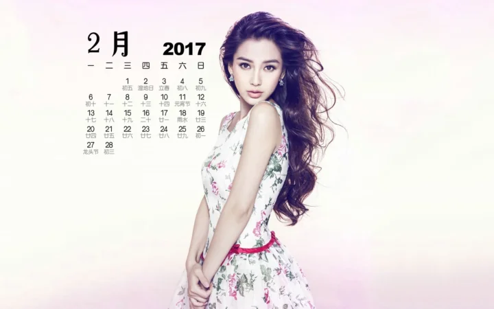 一名成年女性穿着印花连衣裙站在浅粉白色背景前，左上方带有日历文字。