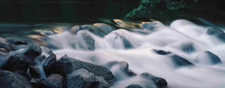 水流如雾般穿过深色岩石，构成宁静的自然风景。